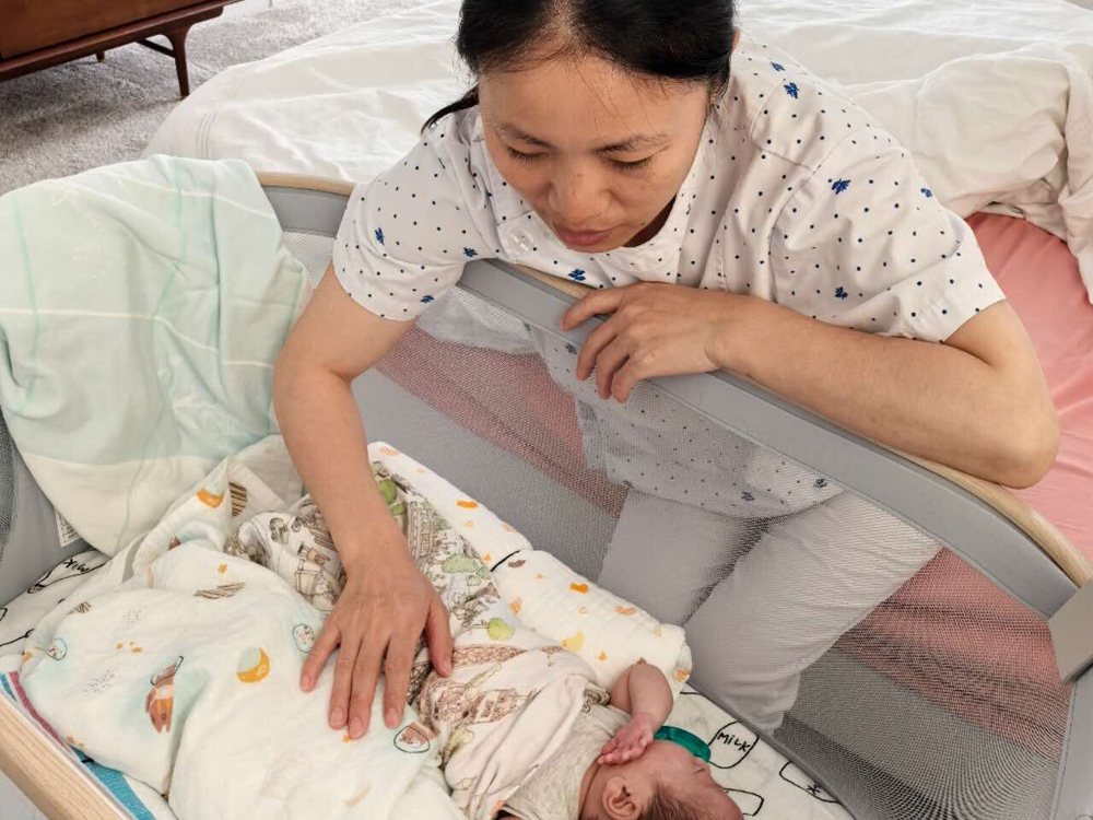 Rainy settling a newborn into a bassinet