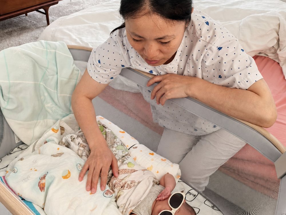 Rainy settling a newborn into a bassinet